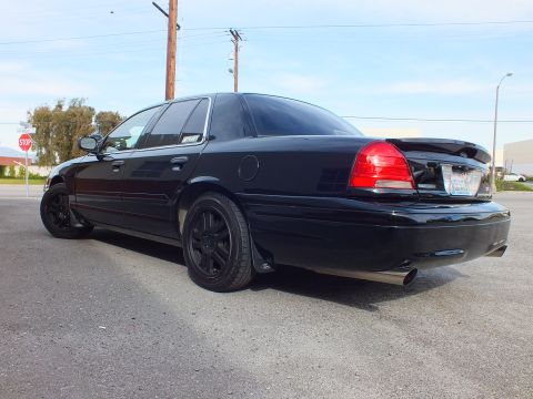 2003 Ford Crown Victoria - Rear passenger view of a blacked-out Crown Victoria with dark tint beside a stop sign.