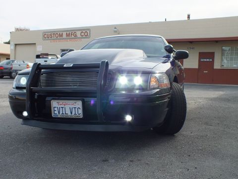 2003 Ford Crown Victoria - Low front view of a black Crown Victoria with brush guard, billet grille and lit headlights.