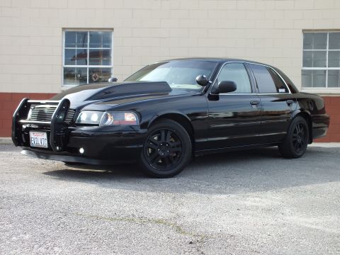 2003 Ford Crown Victoria - Black Ford Crown Victoria, driver-front view, chrome grille guard and black wheels; California plate reads EVIL VIC.