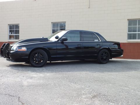 2003 Ford Crown Victoria - Side view of a blacked-out Crown Victoria sedan, brush guard front, dark tint and black wheels.
