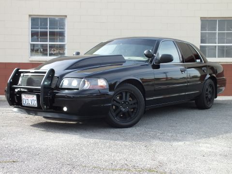 2003 Ford Crown Victoria - Driver-front view of a black Ford Crown Victoria, chrome grille guard and black wheels; plate EVIL VIC.
