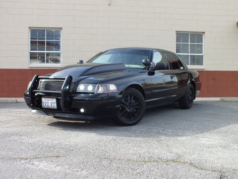 2003 Ford Crown Victoria - Front three-quarter of a black Ford Crown Victoria with chrome grille guard, black wheels and California plate.