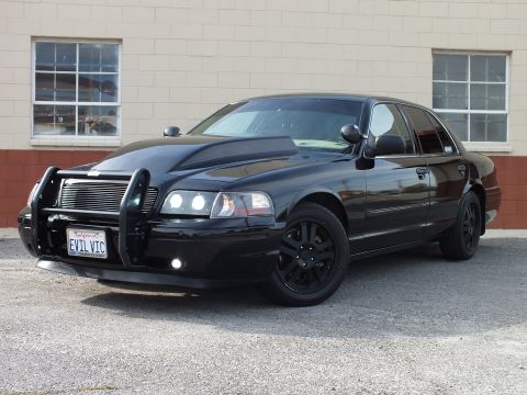 2003 Ford Crown Victoria - Black Crown Victoria sedan front-left view with brush guard, fog lights and black alloy wheels; plate EVIL VIC.