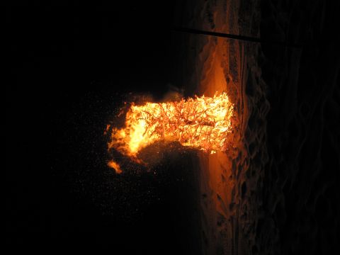 1989 Ford Bronco - A large bonfire burns intensely in the darkness, illuminating the surrounding sandy terrain.