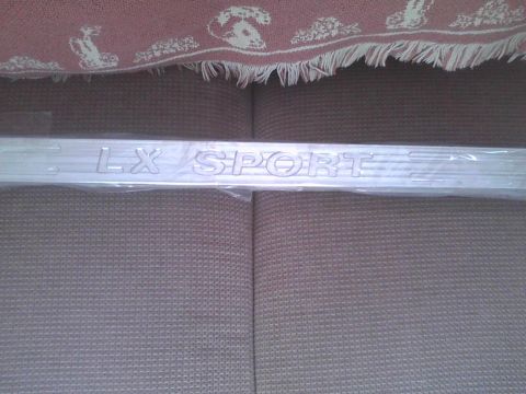2003 Ford Crown Victoria - Embossed 'LX SPORT' trim piece, likely for a vehicle door sill or interior panel.