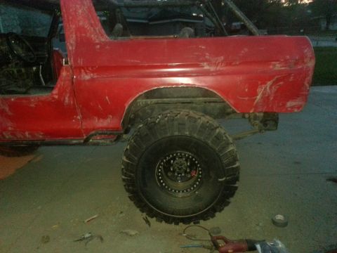 1978 Ford Bronco - A red 1978 Ford Bronco is shown from the side, large tires and a partially disassembled body.