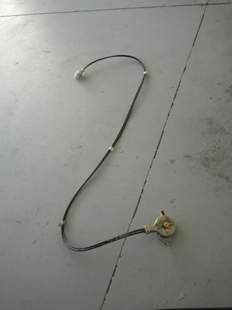 1994 Ford Bronco - A detached rear view mirror adjustment cable lies on a gray concrete surface.