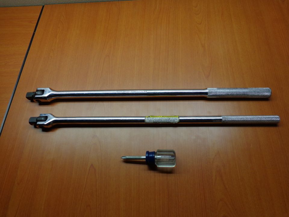 Two long metal breaker bars and a small screwdriver on a wooden surface