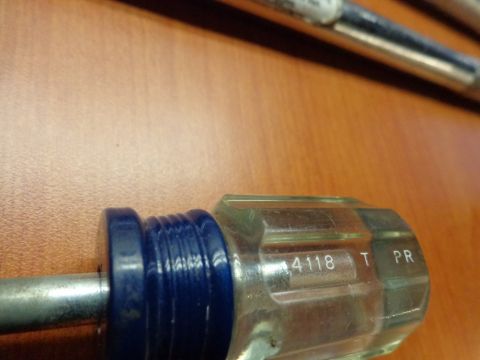 1965 Ford Mustang - A close-up view of a screwdriver handle with visible markings and a blue grip.