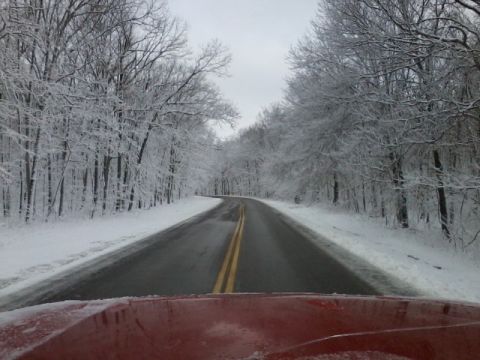1987 Ford Bronco - Driving through a winter wonderland with snow-covered trees lining the road.