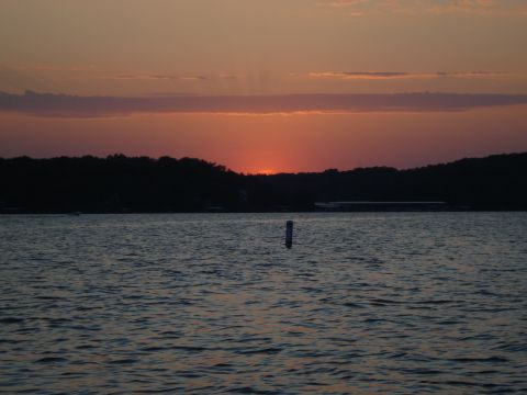 1987 Ford Bronco - The sun sets over a calm lake, casting a warm glow on the horizon.