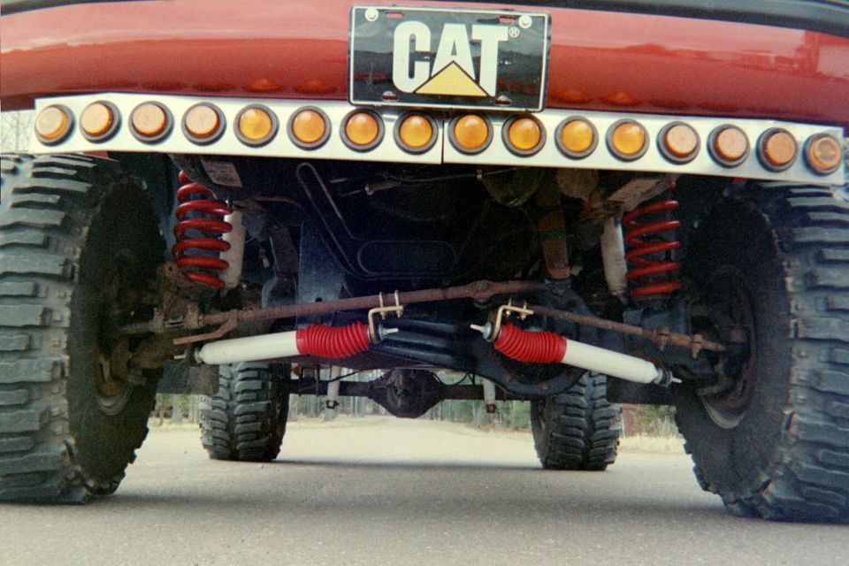 Rear view of a lifted truck showing its suspension, shocks, and a CAT license plate frame