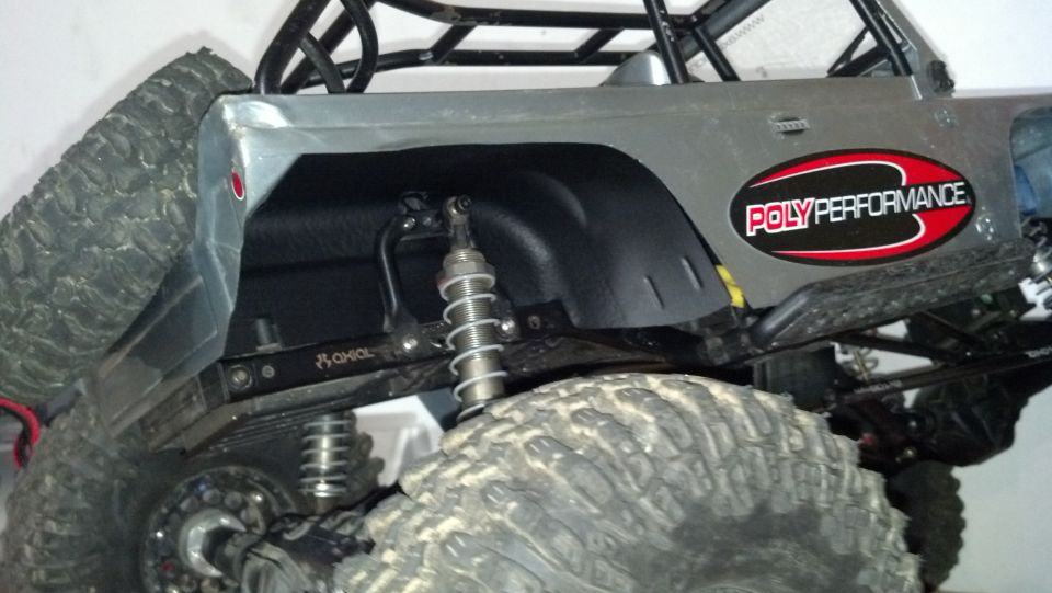 RC rock crawler rear suspension with "Poly Performance" sticker and "Axial" logo on shock