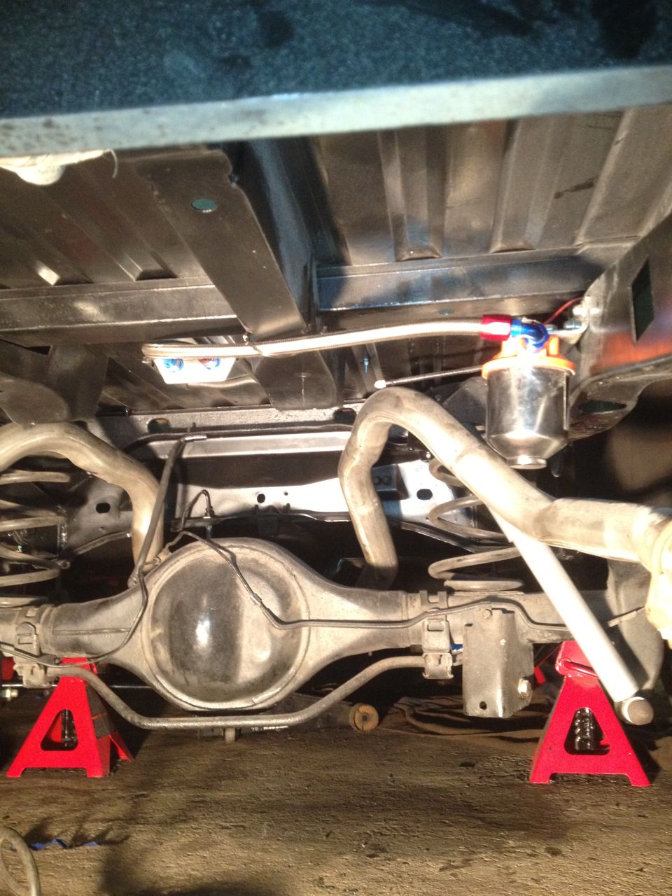 Underside of vehicle on jack stands showing rear axle and fuel filter