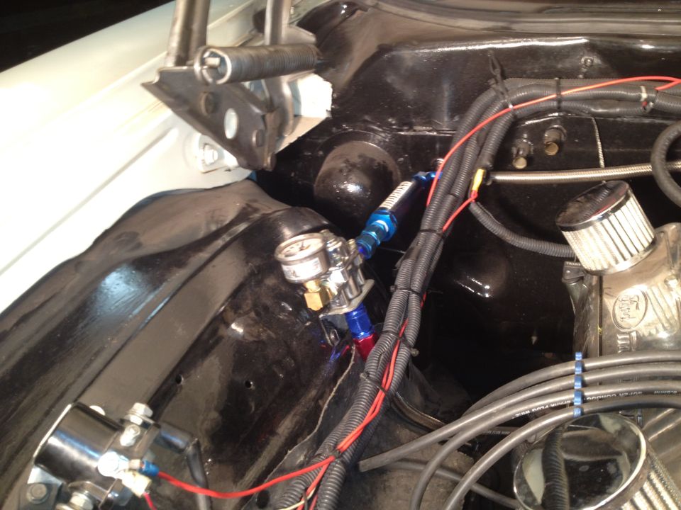 Close-up of fuel pressure regulator and filter in an engine bay