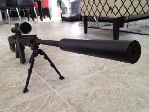2013 Ford Mustang - Rifle with scope and bipod rests on a tiled floor indoors.