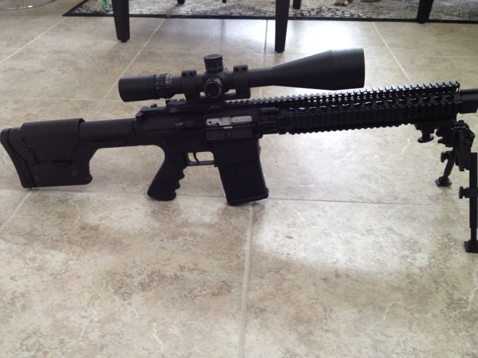 Black rifle with a long scope and bipod on a tiled floor