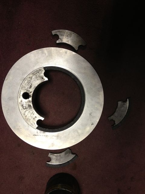 1979 Ford Bronco - A damaged brake rotor and its missing segments lie on a carpeted surface.