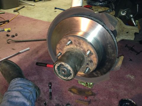 1979 Ford Bronco - Close-up of a vehicle's brake rotor and hub assembly, with tools on the floor.
