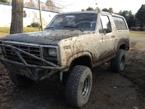 1979 Ford Bronco - This heavily mud-covered 1979 Ford Bronco features a custom front bumper and aggressive off-road tires, suggesting it's built for terrain.