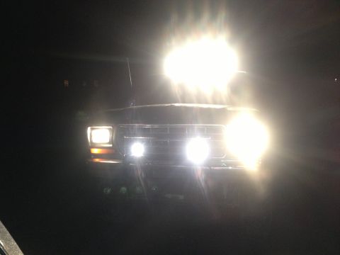 1979 Ford Bronco - The front of a 1978 Ford Bronco is illuminated by its headlights and additional lights in the dark.