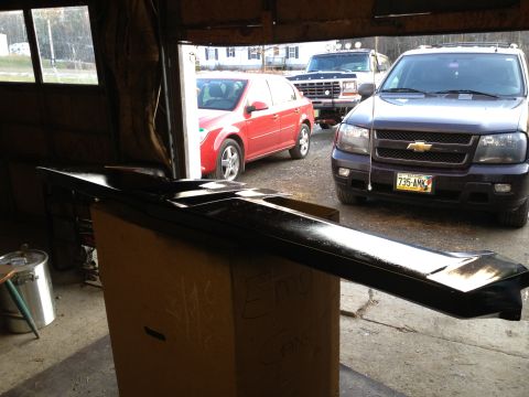 1979 Ford Bronco - A black car part is being worked on inside a garage, with several vehicles visible outside.