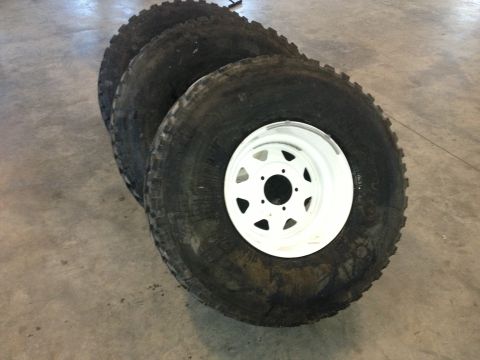 1979 Ford Bronco - A set of four large off-road tires with white rims are displayed on a concrete floor.