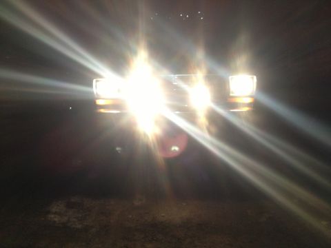 1979 Ford Bronco - The front of a 1979 Ford Bronco is visible with its headlights illuminated.