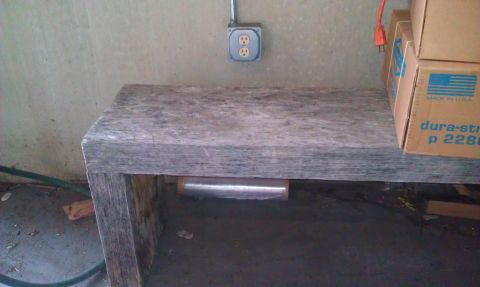 1989 Ford Bronco - A workbench is shown with a wall outlet and stacked boxes, with a roll of plastic wrap underneath.