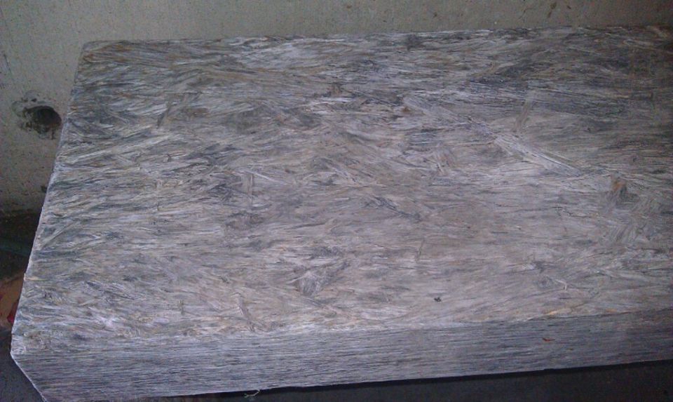 Stack of grey and brown plywood sheets on a dark surface