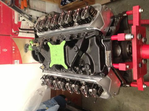 1965 Ford Mustang - Engine assembly on a red stand, a green intake manifold cover and visible valve train components.