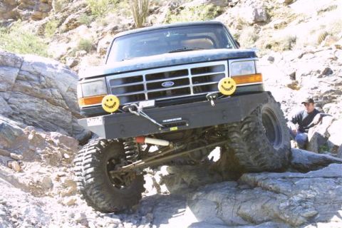 1994 Ford Bronco - A man watches as a modified Ford Bronco tackles a challenging rocky trail.