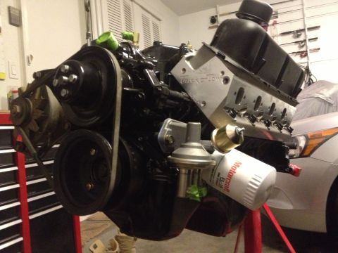 1965 Ford Mustang - A V8 engine is mounted on a stand, with a modern car in the background.