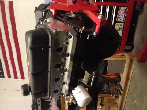 1965 Ford Mustang - Engine assembly with an oil filter attached, displayed against an American flag.