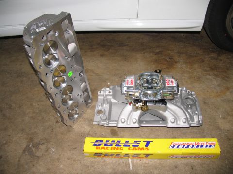 1990 Chevrolet Silverado 1500 - Engine performance parts including an aluminum cylinder head, intake manifold, carburetor, and a box of Bullet Racing Cams are laid out on…