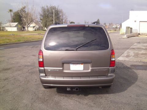 2005 Chevrolet Venture - The rear of a gold Chevrolet Venture minivan is shown parked on a paved surface with buildings in the background.