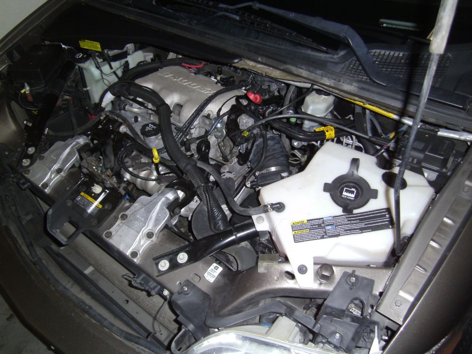 Engine bay of a 2005 Chevrolet Venture with the hood open, showing the engine, coolant reservoir, and various hoses