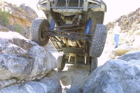 1994 Ford Bronco - A modified off-road vehicle is shown navigating a challenging rocky trail, with a person observing in the distance.