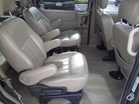 2005 Chevrolet Venture - The interior of this minivan features multiple rows of beige leather captain's chairs and a neutral carpeted floor.