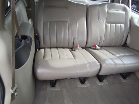 2005 Chevrolet Venture - The interior of a vehicle shows two rows of tan leather seats with visible seatbelts and a cup holder on the side.
