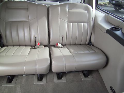 2005 Chevrolet Venture - Interior view of tan leather seats with visible seatbelts and a cup holder.