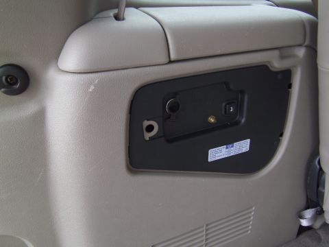 2005 Chevrolet Venture - Close-up view of an interior power outlet and latch mechanism on a vehicle's plastic trim panel.