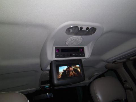 2005 Chevrolet Venture - The interior of a vehicle shows an overhead entertainment system with a screen playing a movie and audio controls.