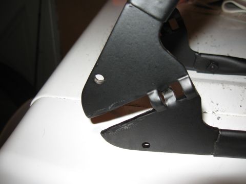 1994 Ford Bronco - Close-up view of a black metal bracket with mounting holes, resting on a white surface.