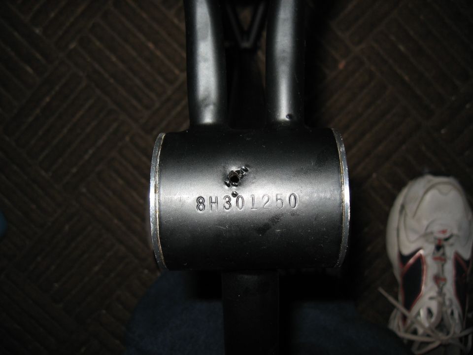 Black metal tube with stamped serial number 8H301250 and a small hole