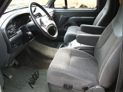 1994 Ford Bronco - The interior of a Ford Bronco shows cloth seats and floor mats with 'Nite' branding.