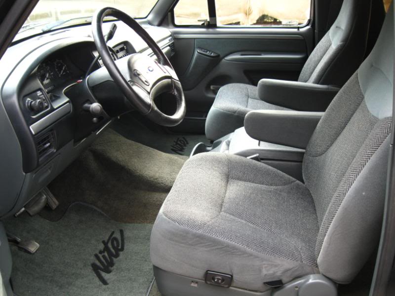 Interior of a Ford Bronco with cloth seats and floor mats that say 'Nite'