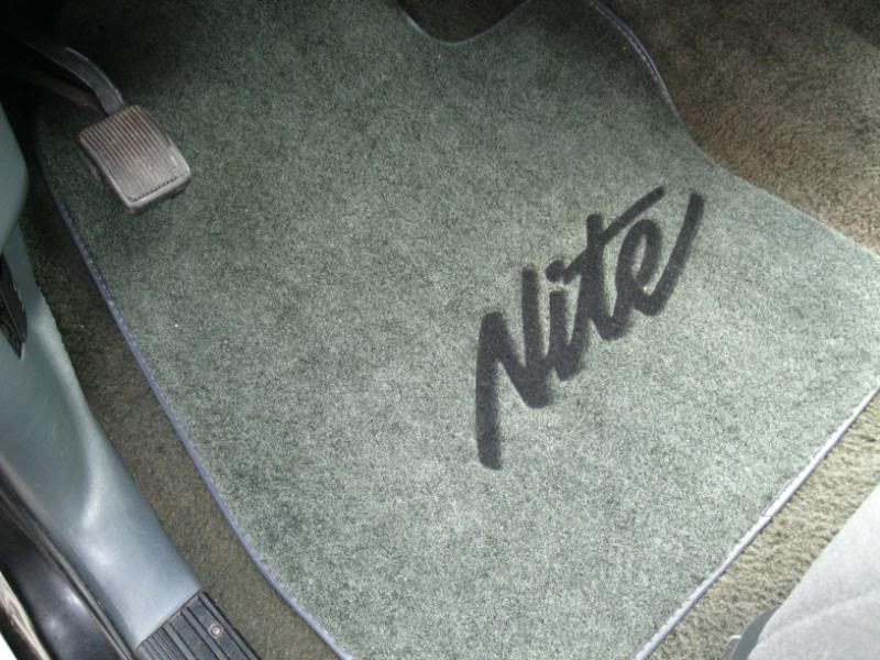 Green floor mat with black "Nite" script logo inside a 1994 Ford Bronco