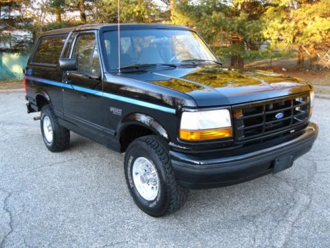 1994 Ford Bronco - Black 1994 Ford Bronco with blue side stripe parked on asphalt.