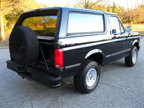 1994 Ford Bronco - Rear three-quarter view of a black Ford Bronco with a spare tire mounted on the back.
